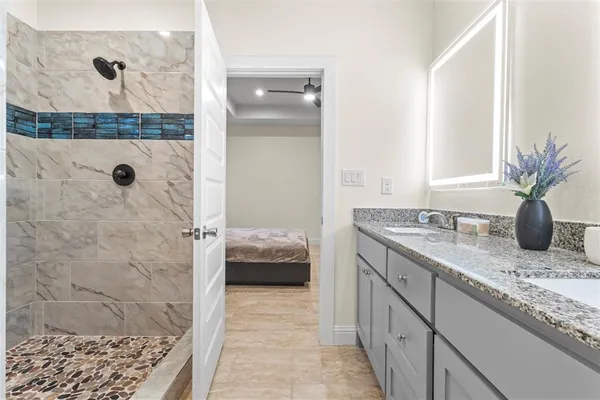 a bathroom with a granite countertop sink a mirror and shower