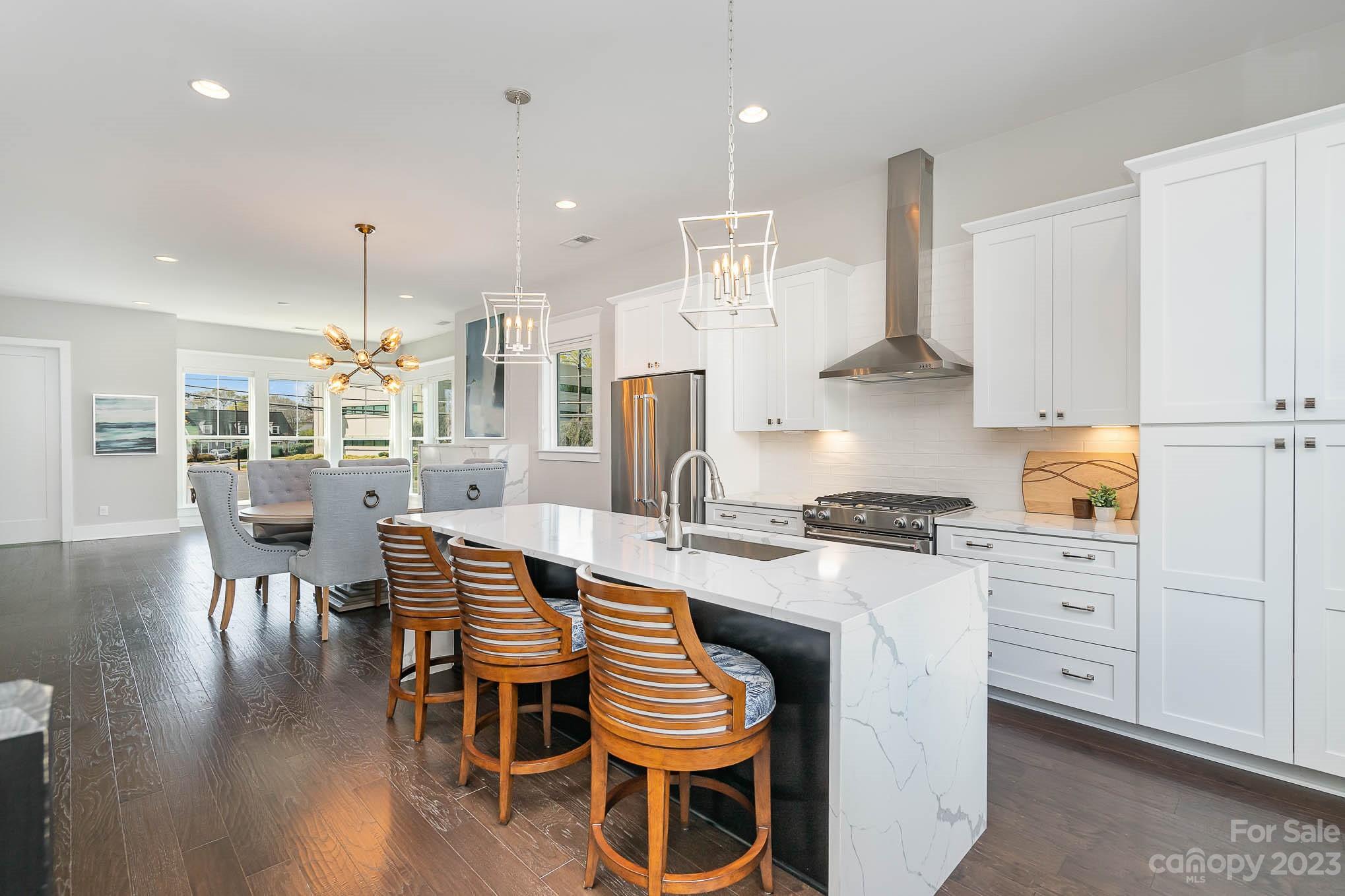 1103 Reece Road Charlotte, NC 28209 - Photo 5 of 32 a kitchen with stainless steel appliances granite countertop a stove a refrigerator a kitchen island a dining table and chairs with wooden floor