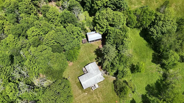 an aerial view of residential house with outdoor space and trees all around