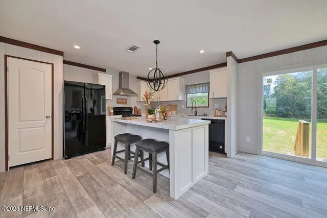 a kitchen with kitchen island granite countertop a refrigerator a sink dishwasher a stove and a dining table with wooden floor