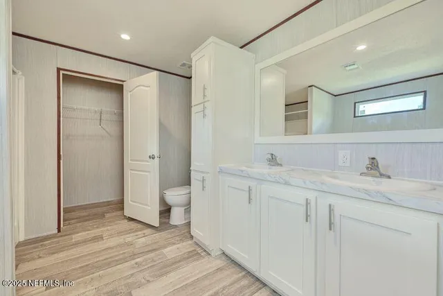 a bathroom with a granite countertop sink a toilet and a large mirror