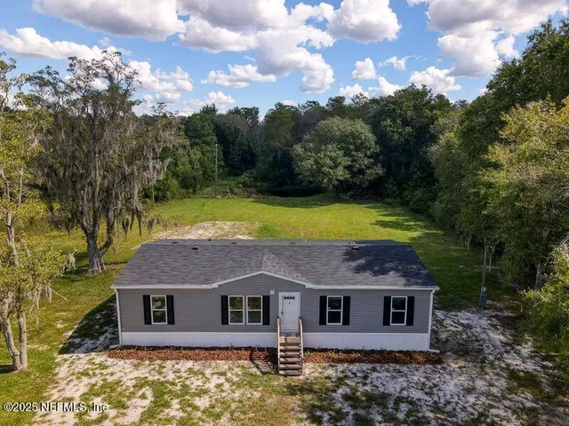 a view of a house with a yard and large tree