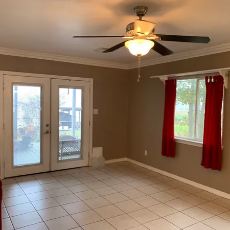 an empty room with windows and fan