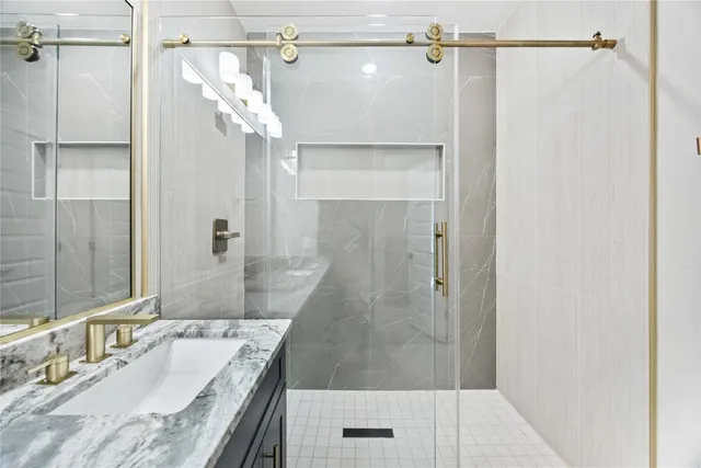 a bathroom with a granite countertop shower sink and mirror