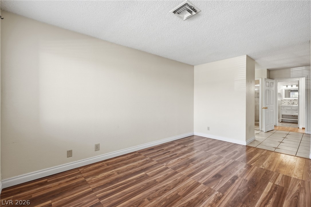 3971 Spring Leaf Drive Las Vegas, NV 89147 - Photo 34 of 48 Rich hardwood-style flooring leads into a functional primary bedroom with direct bathroom access.
