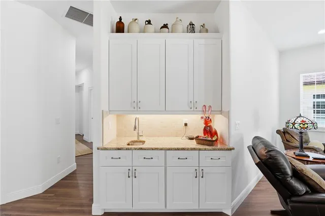 a kitchen with white cabinets and sink