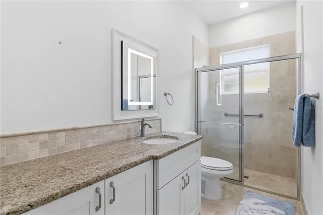a bathroom with a granite countertop sink a toilet and shower