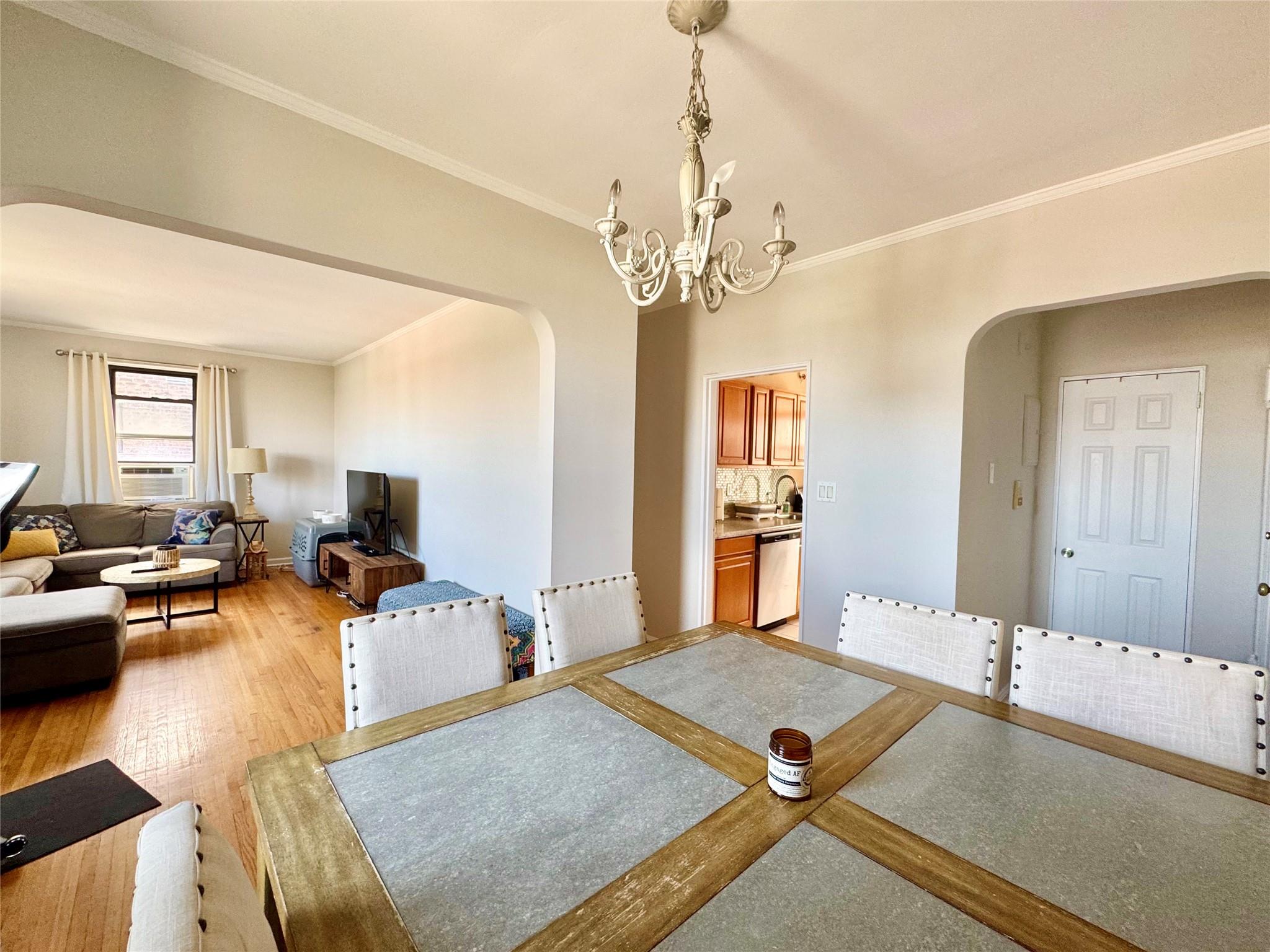 128-11 Newport Avenue, Unit 4A Queens, NY 11694 - Photo 5 of 18 Dining space featuring arched walkways, a chandelier, light wood-type flooring, and crown molding