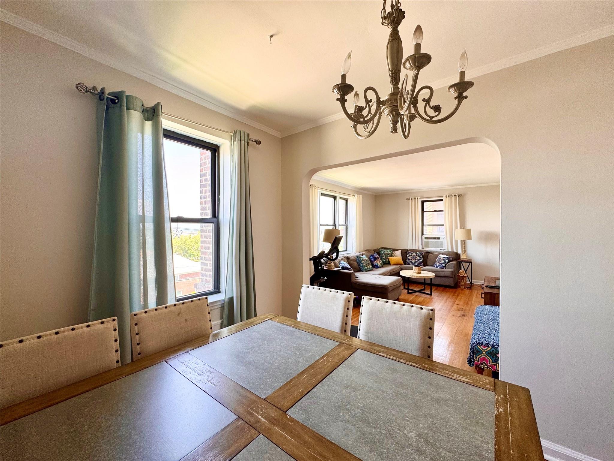 128-11 Newport Avenue, Unit 4A Queens, NY 11694 - Photo 6 of 18 Dining area with arched walkways, ornamental molding, a chandelier, and wood finished floors