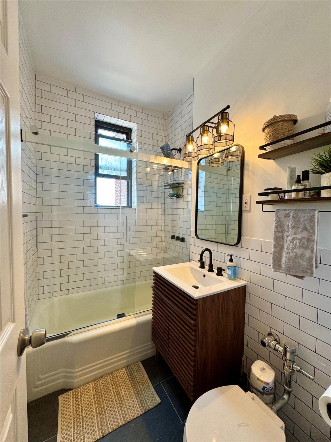 128-11 Newport Avenue, Unit 4A Queens, NY 11694 - Photo 7 of 18 Bathroom featuring tile walls, vanity, enclosed tub / shower combo, and tile patterned floors