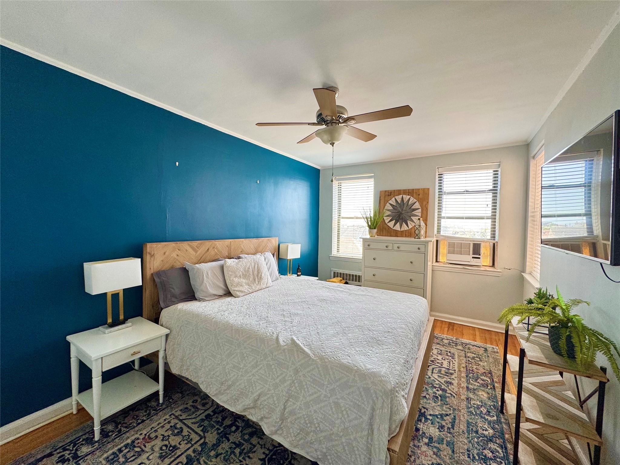 128-11 Newport Avenue, Unit 4A Queens, NY 11694 - Photo 8 of 18 Bedroom with wood finished floors, crown molding, cooling unit, ceiling fan, and radiator