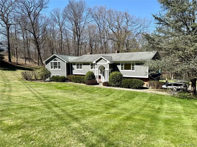 a front view of a house with a garden and trees