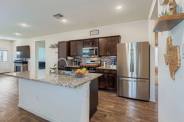 a kitchen with stainless steel appliances granite countertop a refrigerator and a stove