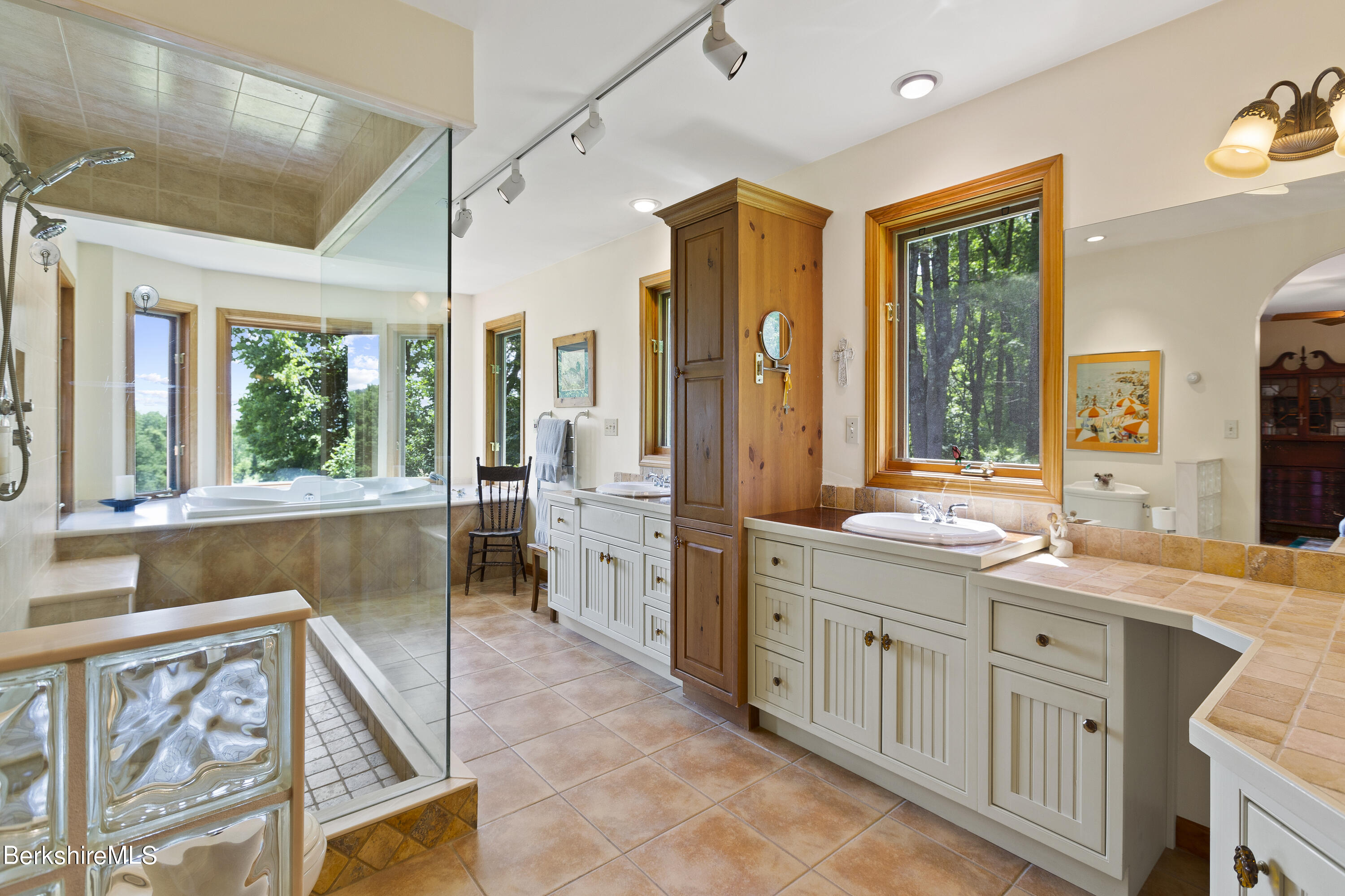 3025 Mt Anthony Road Bennington, VT 05201 - Photo 36 of 54 a bathroom with a double vanity sink a large mirror and a bathtub next to a window