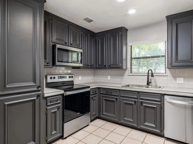 a kitchen with granite countertop a refrigerator and a stove top oven