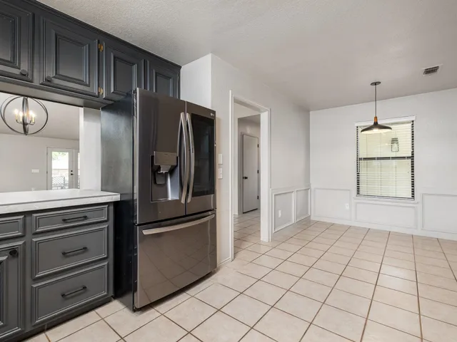 an empty room with a chandelier fan and windows