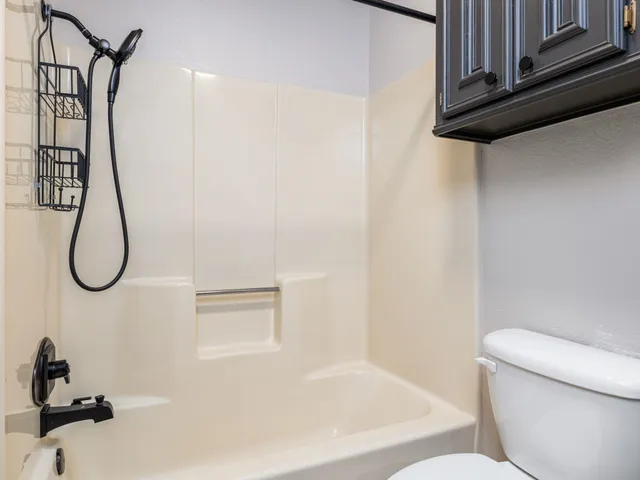 an empty room with a chandelier fan and windows