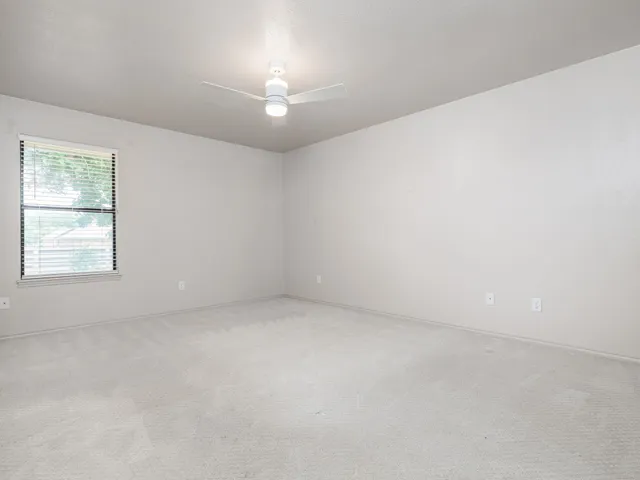 an empty room with a window and a ceiling fan
