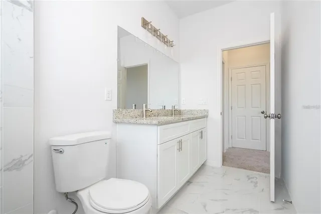 a bathroom with a granite countertop sink toilet and shower