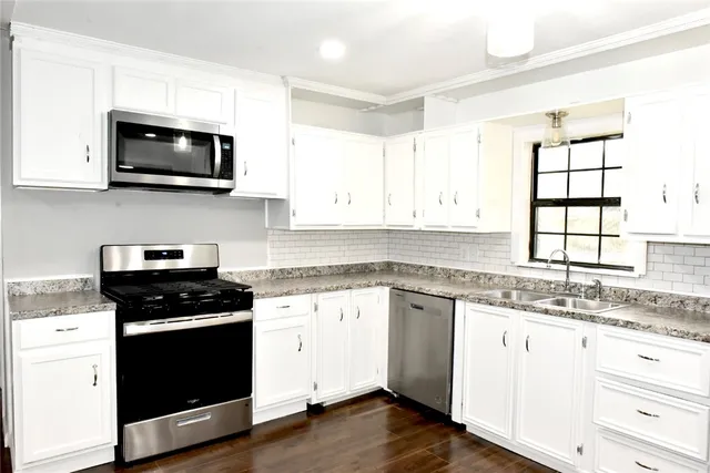 a kitchen with granite countertop white cabinets and black appliances
