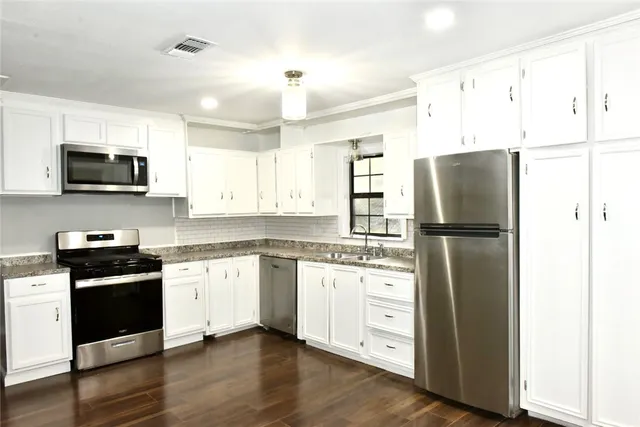 a kitchen with granite countertop a refrigerator stove and sink