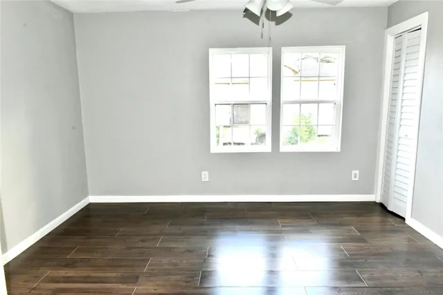 an empty room with wooden floor and windows