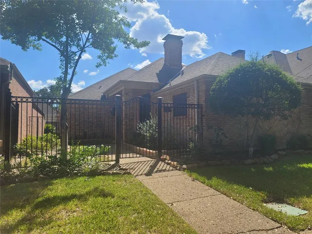 a backyard of a house with table and chairs plants and large tree