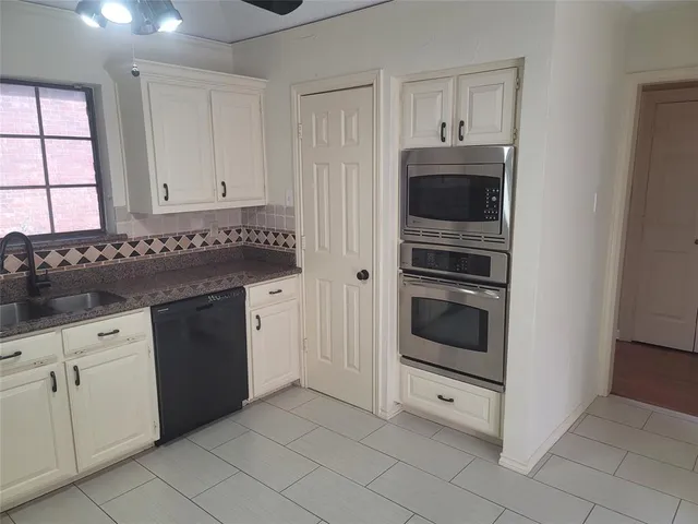 a kitchen with granite countertop white cabinets and stainless steel appliances
