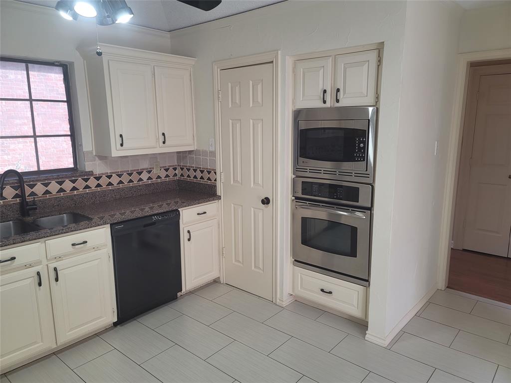 5719 Encore Drive Dallas, TX 75240 - Photo 4 of 21 a kitchen with granite countertop white cabinets and stainless steel appliances