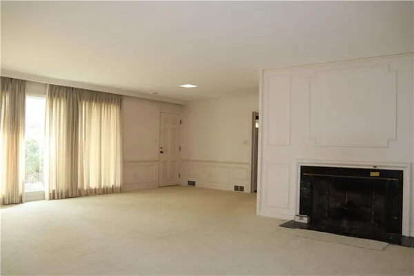 an empty room with windows and fireplace