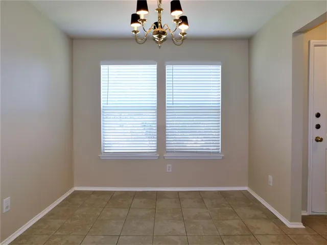 an empty room with windows and chandelier fan