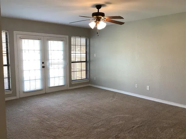 an empty room with windows and ceiling fan