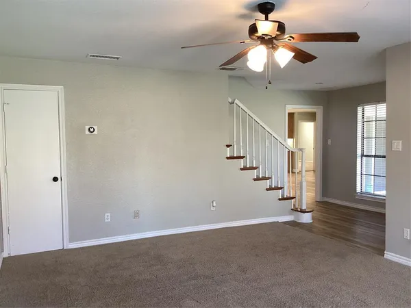 a view of an empty room with a chandelier fan