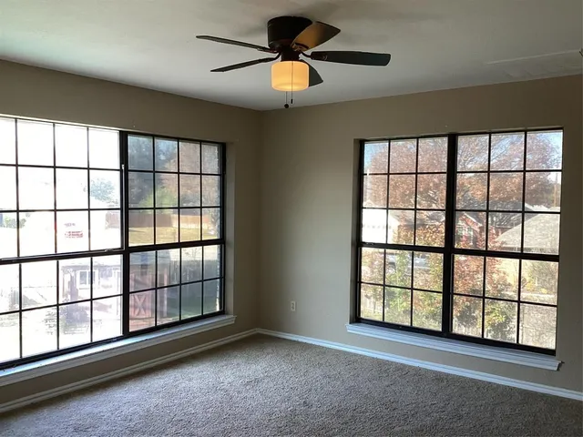 a view of room with windows and ceiling fan