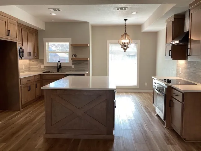 a kitchen with granite countertop a stove a sink a refrigerator and wooden floor