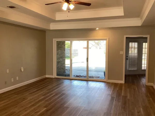 a view of an empty room with wooden floor and a window