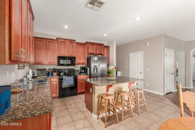 a kitchen with stainless steel appliances kitchen island granite countertop a refrigerator and cabinets