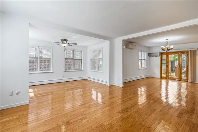 a view of an empty room with window and wooden floor
