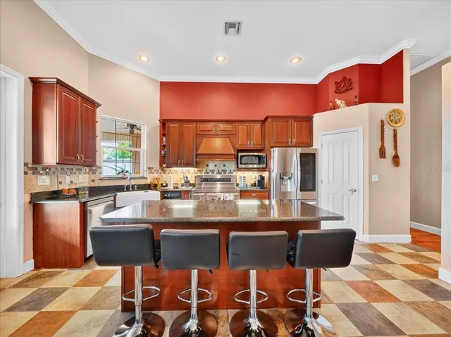 a kitchen with stainless steel appliances granite countertop a refrigerator a stove a sink and a microwave