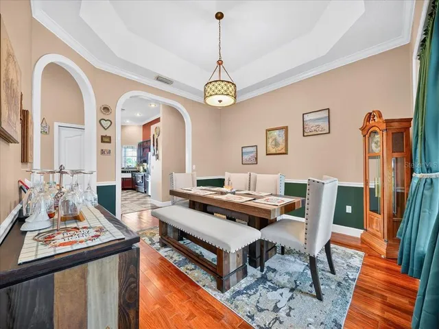 a dining room with wooden floor a chandelier a wooden table and chairs