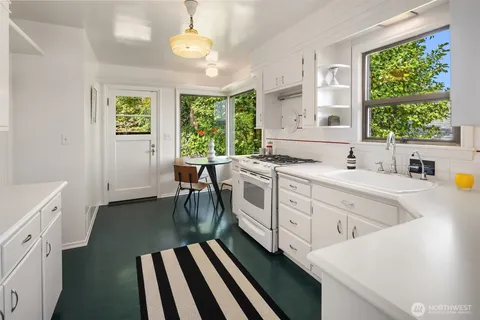 a kitchen that has a sink window and cabinets
