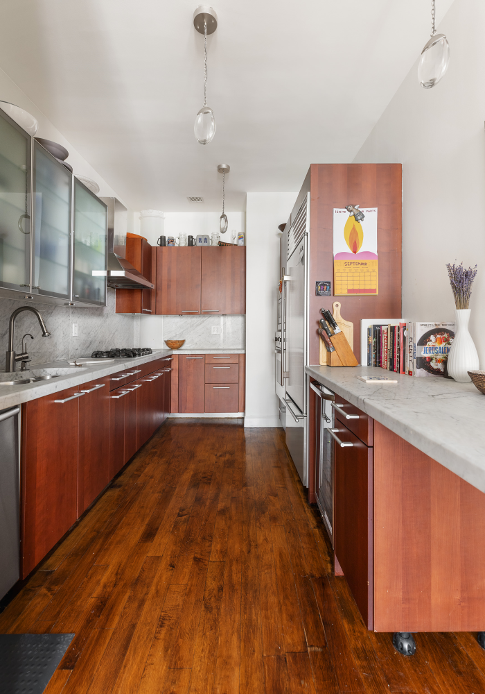 42 East 20th Street, Unit 7A Manhattan, NY 10003 - Photo 6 of 13 a kitchen with stainless steel appliances granite countertop a sink and wooden cabinets