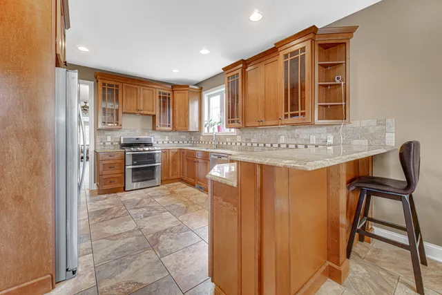 a kitchen with stainless steel appliances granite countertop a stove top oven a sink and a refrigerator