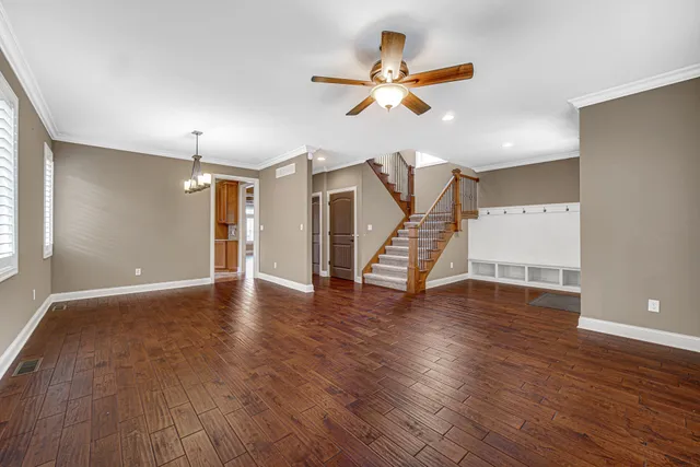 a view of an empty room with wooden floor and a ceiling fan