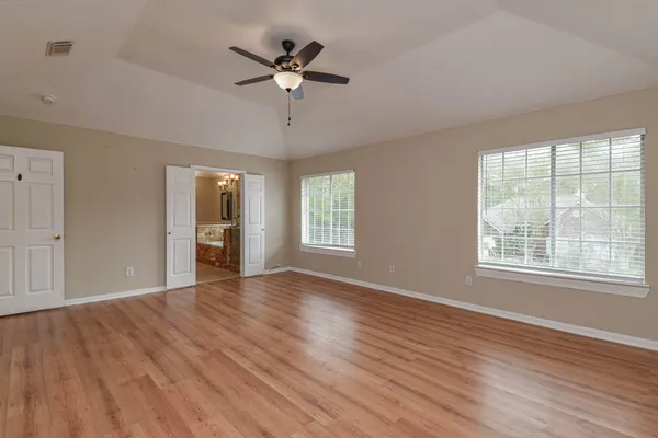a view of an empty room with a window and wooden floor
