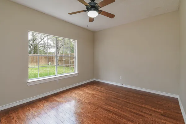 a view of an empty room with a window and wooden floor