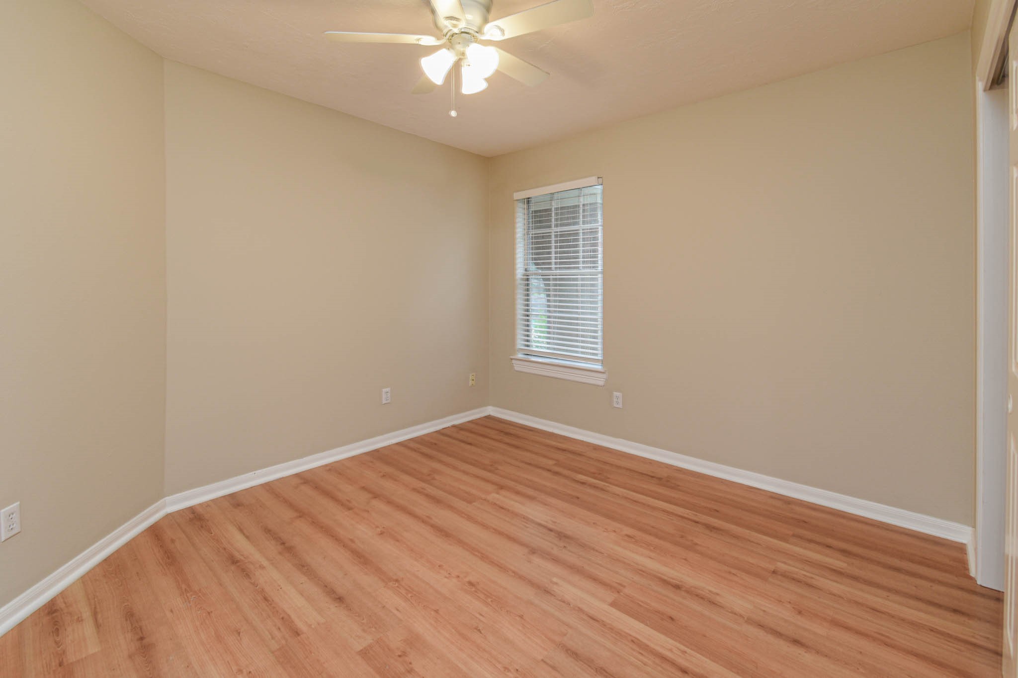 8806 Edenbridge Street Spring, TX 77379 - Photo 5 of 25 an empty room with wooden floor fan and windows