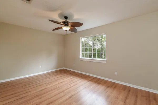 a view of empty room with wooden floor and fan