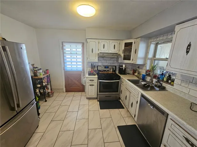 a kitchen with stainless steel appliances a sink stove refrigerator and a window