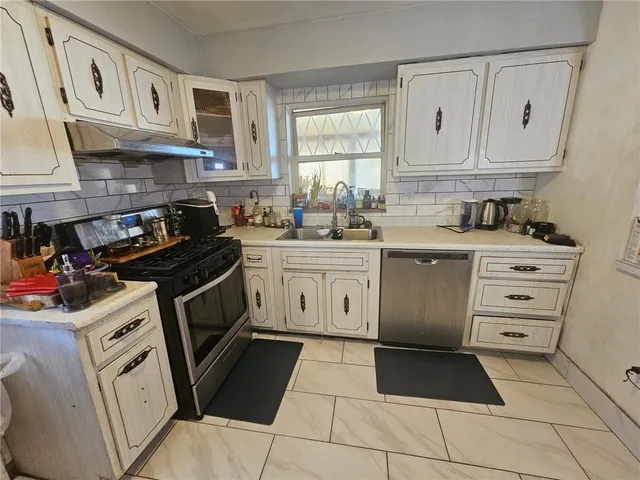 a kitchen with stainless steel appliances a stove a sink and a refrigerator